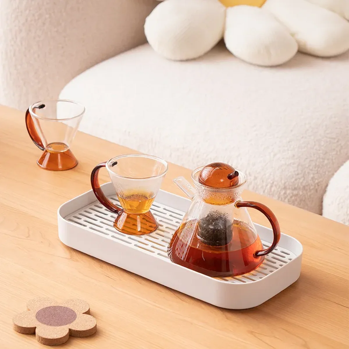 A white slatted rectangular drip tray holding a glass teapot and two cups on a wooden table
