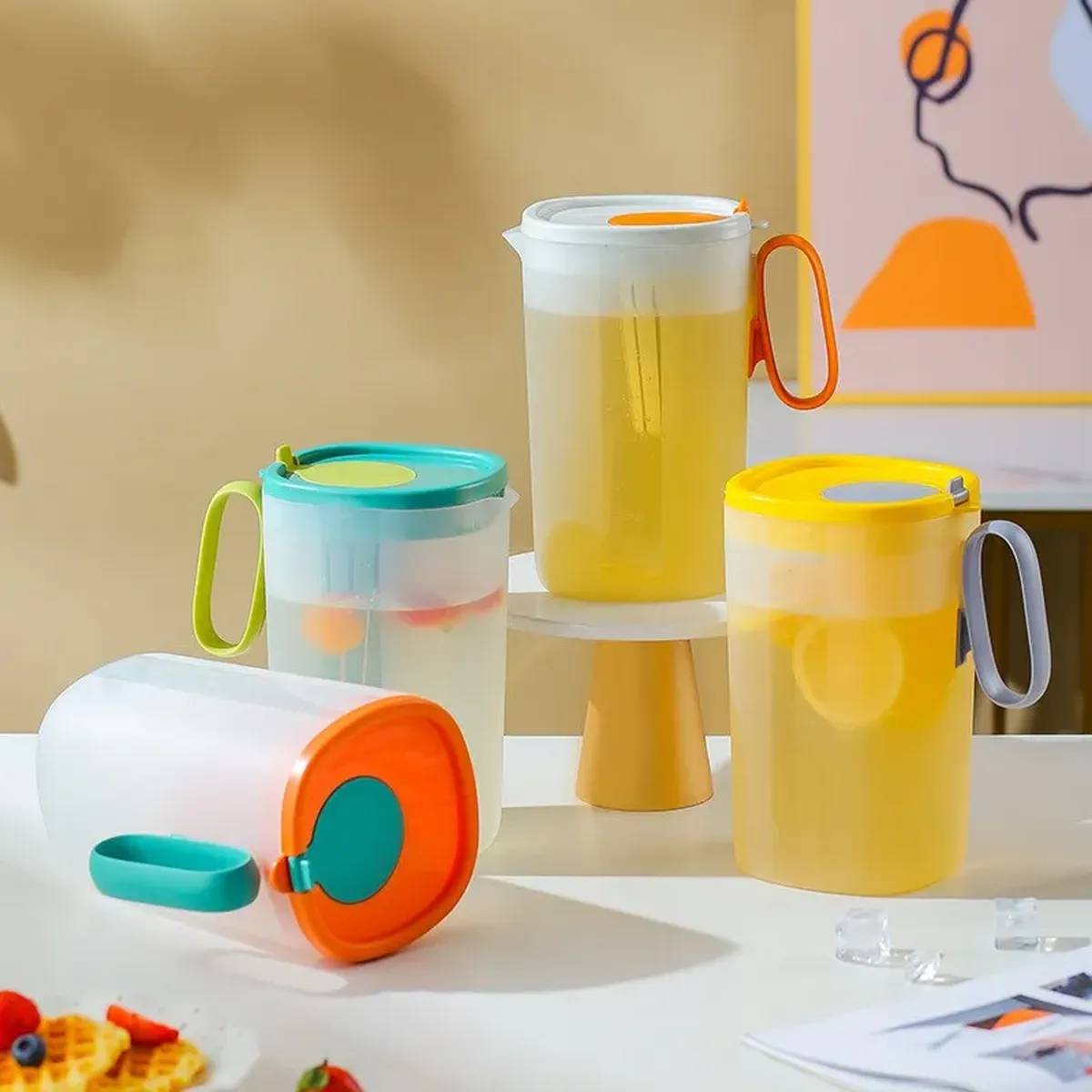 Four colourways of the same moulded plastic jug — orange, teal, yellow and translucent white — showing one model produced in several colours