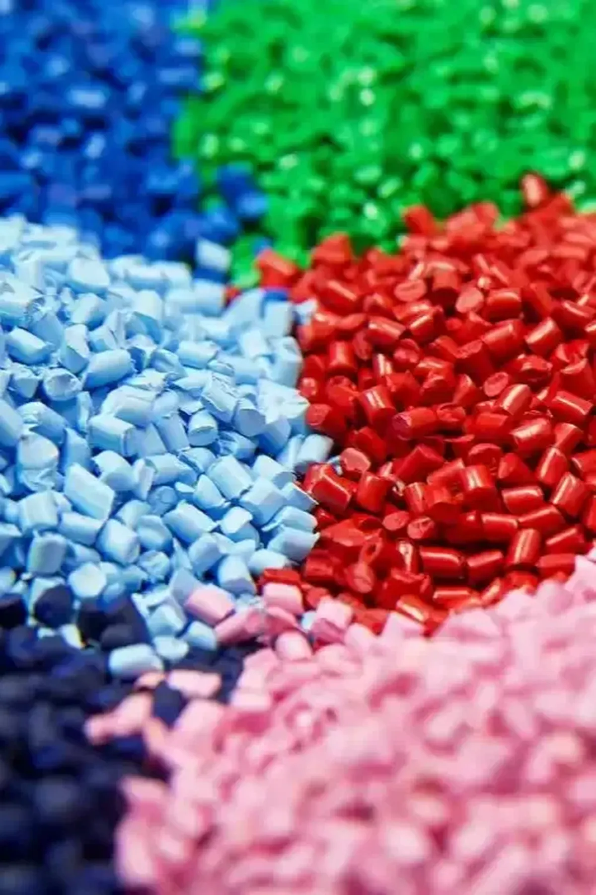 Close-up of blue, green, light blue, red, pink and dark plastic pellets used as moulding feedstock