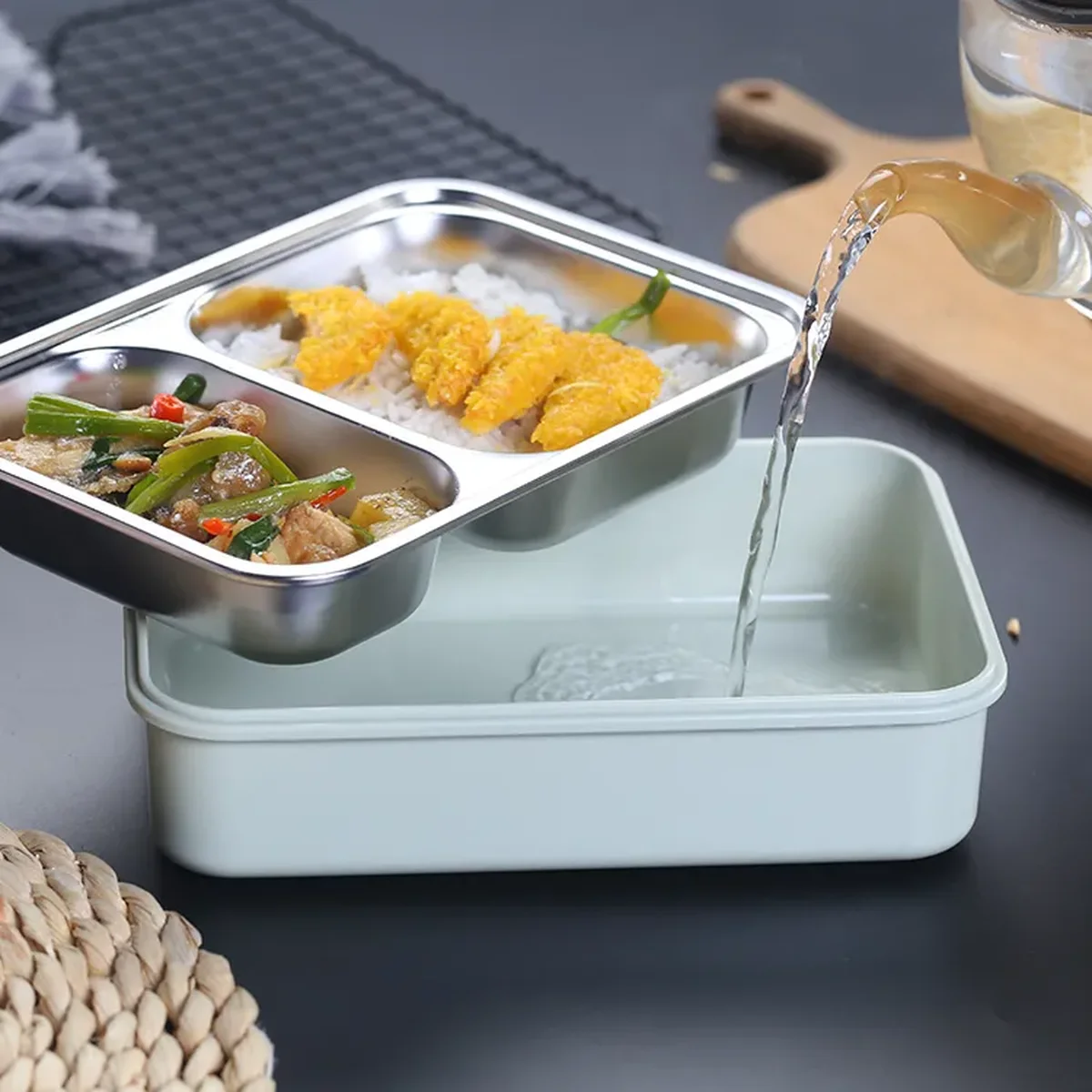 A two-compartment stainless steel tray lifted clear of its base while an amber liquid is poured into the base it was lifted from