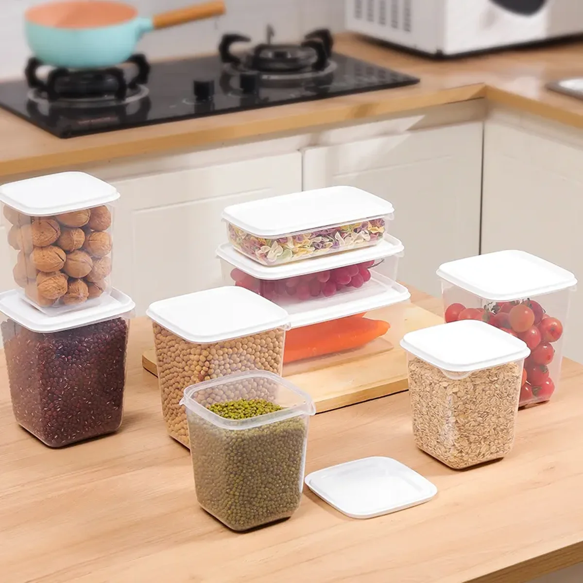 Tall clear plastic pantry canisters of several heights filled with dry goods, standing on light wood